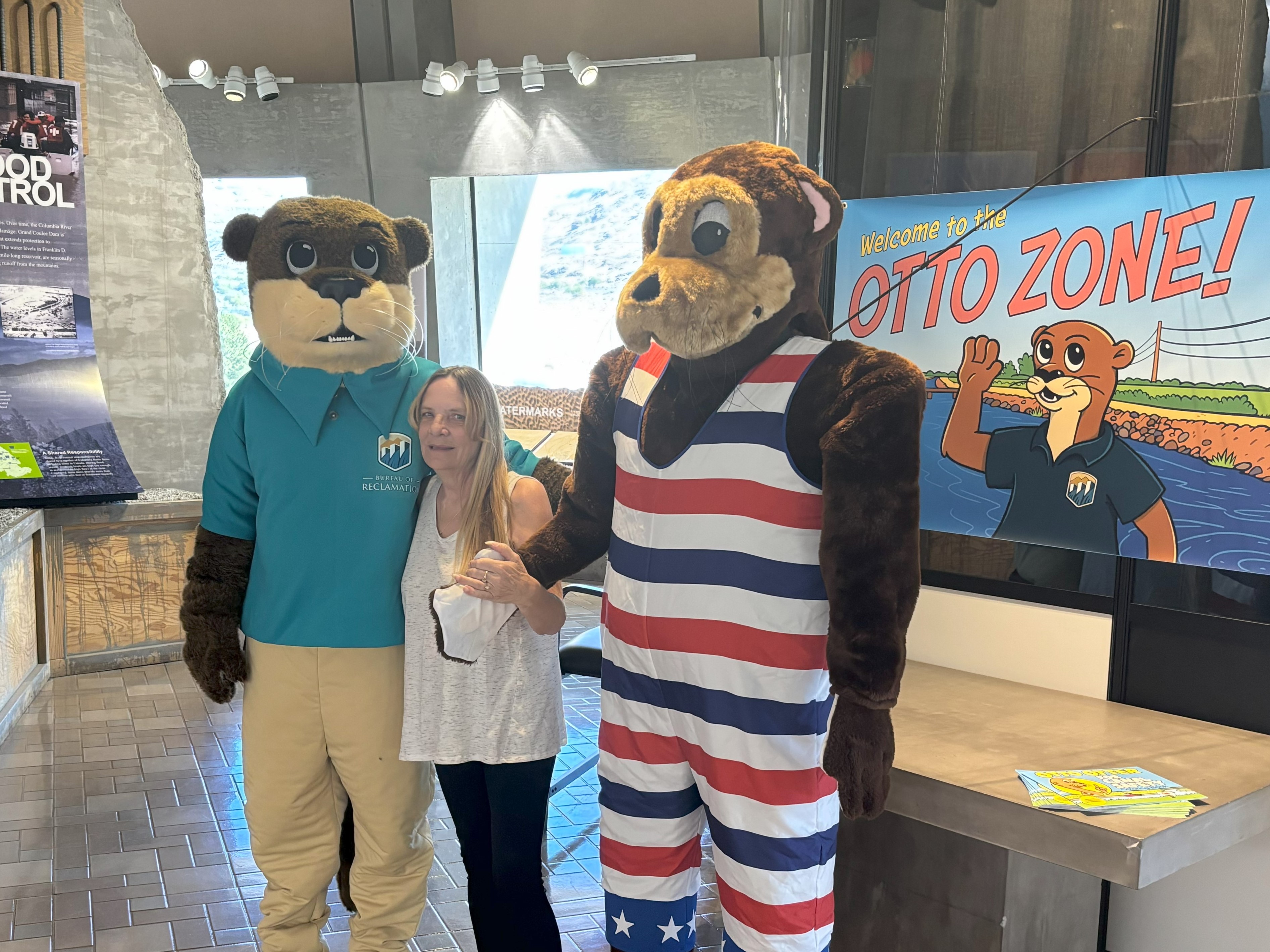 Lori Presnell, center, creator of Otto Otter, stands between two Otto Otter costumes at Grand Coulee Dam’s visitor center.